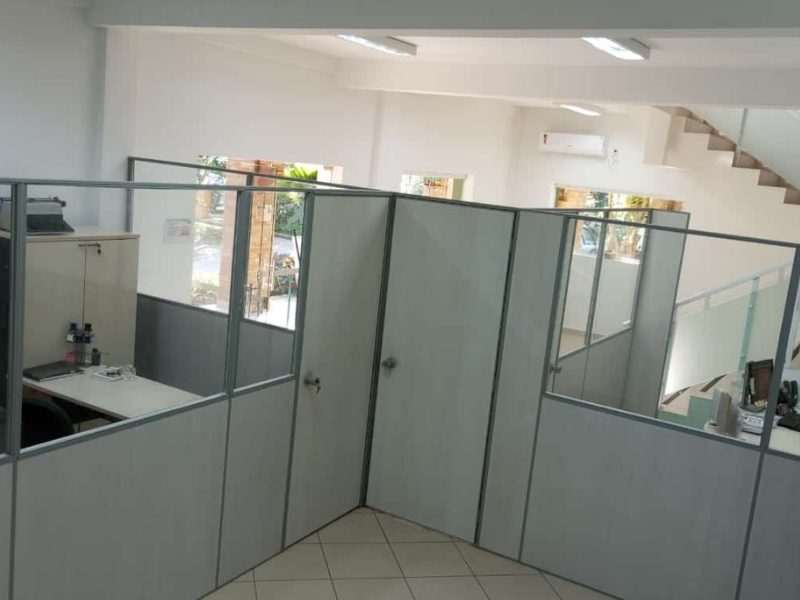 Divisórias com vidro separando estações de trabalho num escritório