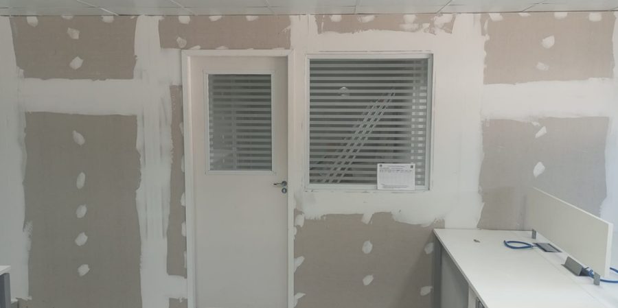 Paredes de drywall com porta e janela, com as juntas tratadas e os parafusos cobertos de massa, antes da pintura